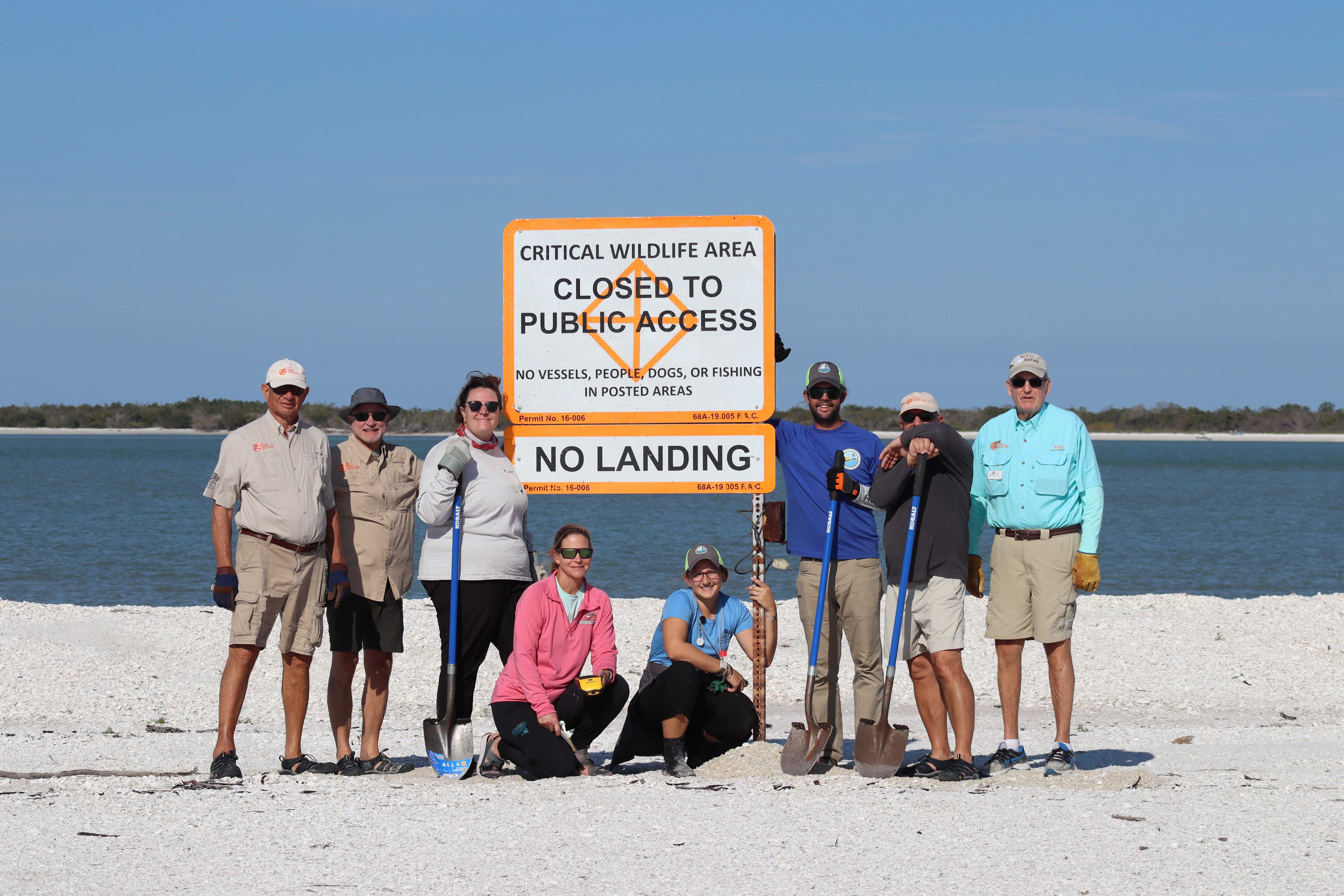 A group of volunteers in Southwest Florida post in front of a sign